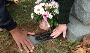 Mary McCarthy Hines and her husband, Charles, touch the grave of their stillborn daughter, Virginia, in late October. "A m.o.m.s. peace" helped order and install a grave marker for Virginia and honor her life through a remembrance program. (CNS photo/courtesy Kara Palladino) 
