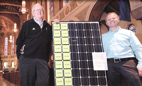 Father Al Hirt, left, holds one of the solar panels that will provide energy to light the campus from church, to parish center, to maintenance garage, to parking lot. (CT Photo/E.L. Hubbard)