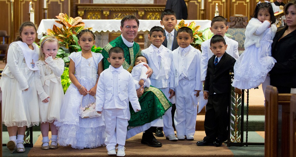 Father Jamie Weber, pastor of St. Cecilia, poses for a photo with a group of recently baptized students. (Courtesy Photo)