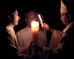 The Most Reverend Dennis M. Schnurr, Archbishop of Cincinnati, lights a candle with the flame of the Easter Candle during the Easter Night Vigil in the Holy Night on Holy Saturday, March 26, 2016, at the Cathedral of Saint Peter in Chains in Cincinnati.
