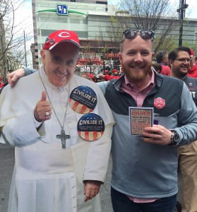 A man holding a card promoting the Archdiocese of Cincinnati's "Civilize It'" campaign stands with a cutout of Pope Francis April 4 during festivities before the Cincinnati Reds season-opening game. The campaign is designed to encourage people to be respectful of the views of others during the electoral campaigns. (CNS photo/Mimi London, Archdiocese of Cincinnati)