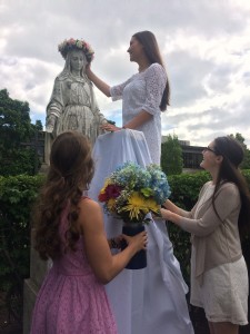 Lehman Catholic student Diana Gibson crowns Mary as Emma Simpson (right bottom) and Cassidy Hemm (left bottom) bring gifts of flowers to the Holy Mother during the recent May Crowning ceremony held at Lehman Catholic High School. (Courtesy Photo)