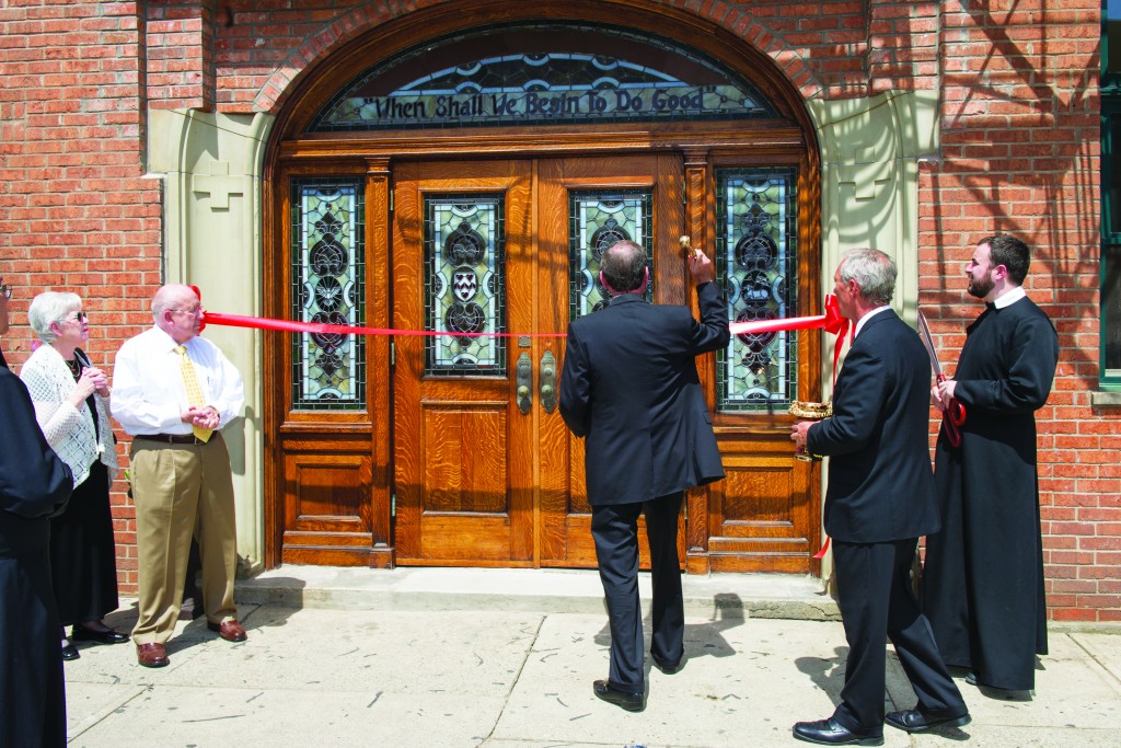 Archbishop Dennis M. Schnurr blesses the front door of the new residence of the St. Philip Neri Community in Formation at 118 E. 12th Street in Over-the-Rhine. At far right is Father Jon-Paul Bevak, moderator of the Oratory, holding ceremonial scissors that would be used to cut the ribbon to officially open the facility. The ceremony took place April 18. (CT Photo/Colleen Kelly)