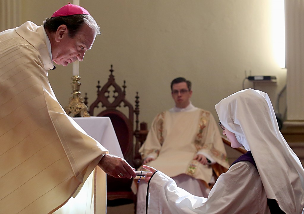 Archbishop Dennis Schnurr hands a scroll to Sister Antonietta Maria as she accepts her new name during Holy Mass to celebrate the erection of the Children of Mary Motherhouse at the Our Lady of the Holy Spirit Center in Norwood Monday, Nov. 21, 2016. (CT Photo/E.L. Hubbard)