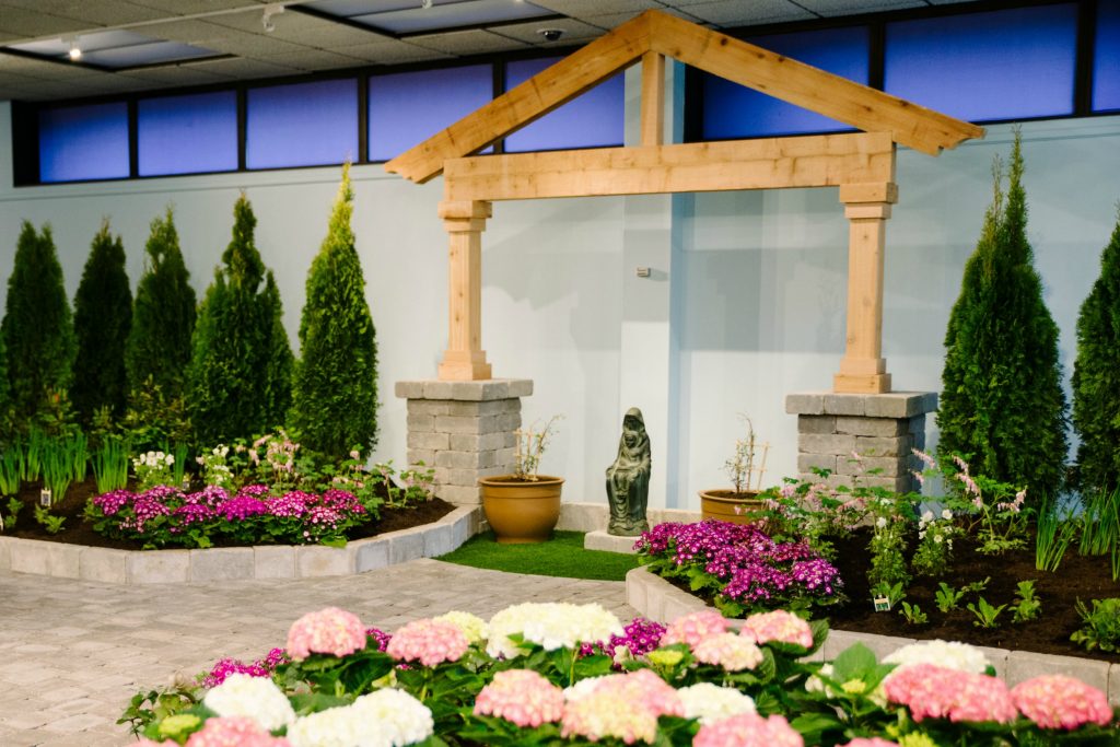 A statue of St Joseph once sold by John Stokes sits framed by Arborvitae bushes and Cineraria, Siberian Iris, meadow sage (“Mary’s Shawl”) and snowdrop (Anemone sylvestris, “Flower of the Field”). (COURTESY PHOTOS/BRIANA SNYDER)