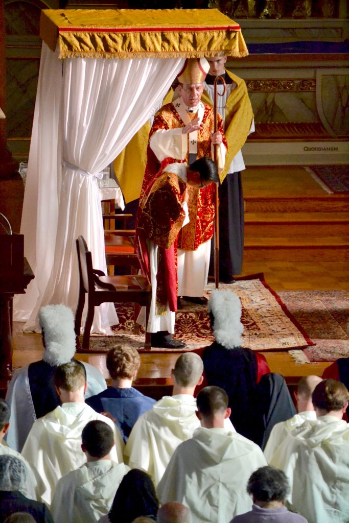 Archbishop Schnurr, standing under the canopy built for the Mass, reads a prayer. Deacon Duy Nguyen, who will be ordained a priest next month, is beside him. (CT/Photo Gail Finke)