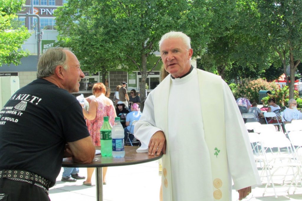 Father Byrne speaks to a kilt-clad gentleman following the outdoor Mass (CT Photo/Gail Finke)