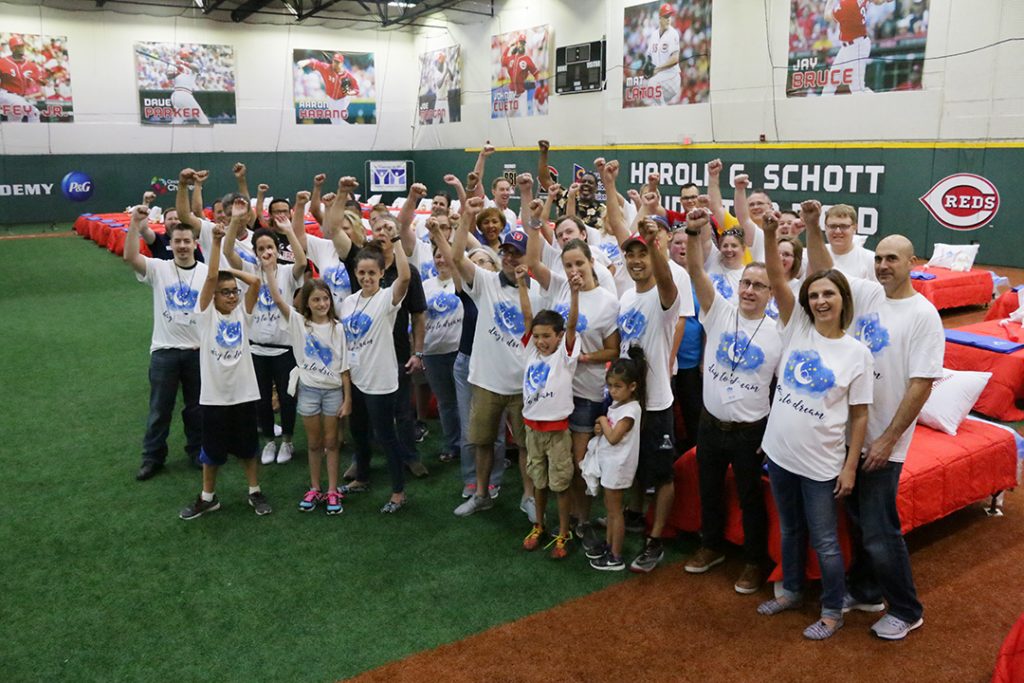 Some of the 100 volunteers from local companies declare victory after assembling and making the beds set up at the P&G Cincinnati MLB Youth Academy the night before the event. Volunteers from the City Dash courier company and members of Crossroad Church’s “Mighty Men” delivered every bed by Saturday night, so that each child who received one went to sleep in it.  (Courtesy Photo)