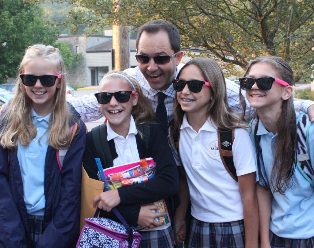 St. Andrew – St. Elizabeth Ann Seton School’s principal, Mr. Mark Wilburn, greeted sixth grade students, Sydnie Reith of Goshen, Avery May of Goshen, Grace Evans of Milford and Marin Warman of Goshen each with a pair of cool shades on their first day of the new school year. (Courtesy Photo)