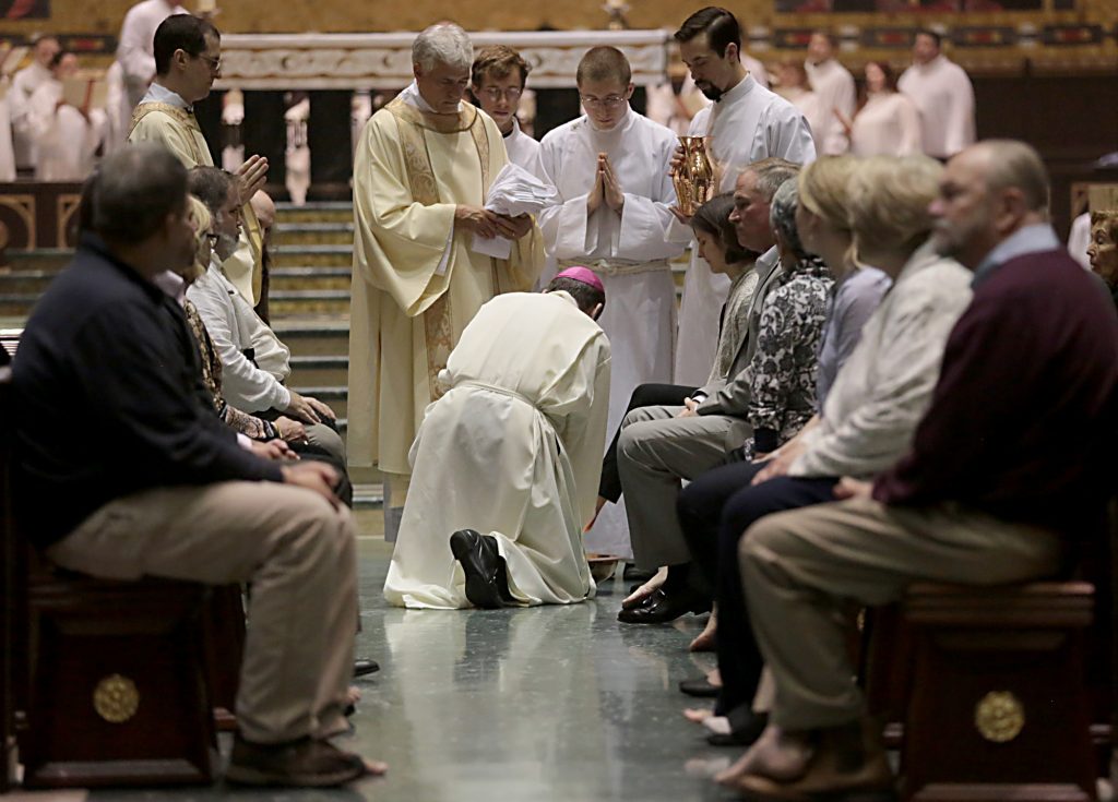 Archbishop Dennis Schnurr kneels to wash the feet of a parishioner during the Solemn Evening Mass of the Lord’s Supper on Holy Thursday at the Cathedral of Saint Peter in Chains Cathedral in Cincinnati March 29, 2018. (CT Photo/E.L. Hubbard)