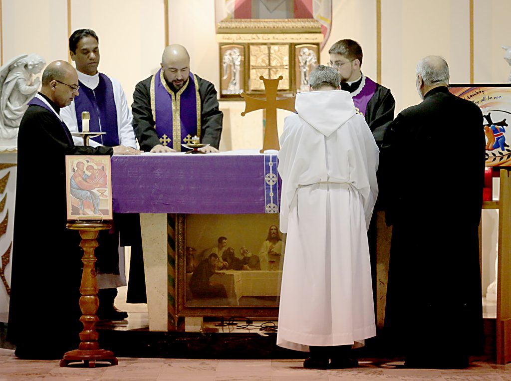 Faith leaders place their hands on the Altar before giving each other, and then those gathered, the Sign of Peace during the Lenten Prayer Service for Christian Unity and Religious Freedom at St. Anthony of Padua Maronite Catholic Church in Cincinnati Saturday, Mar. 10, 2018. (CT Photo/E.L. Hubbard)