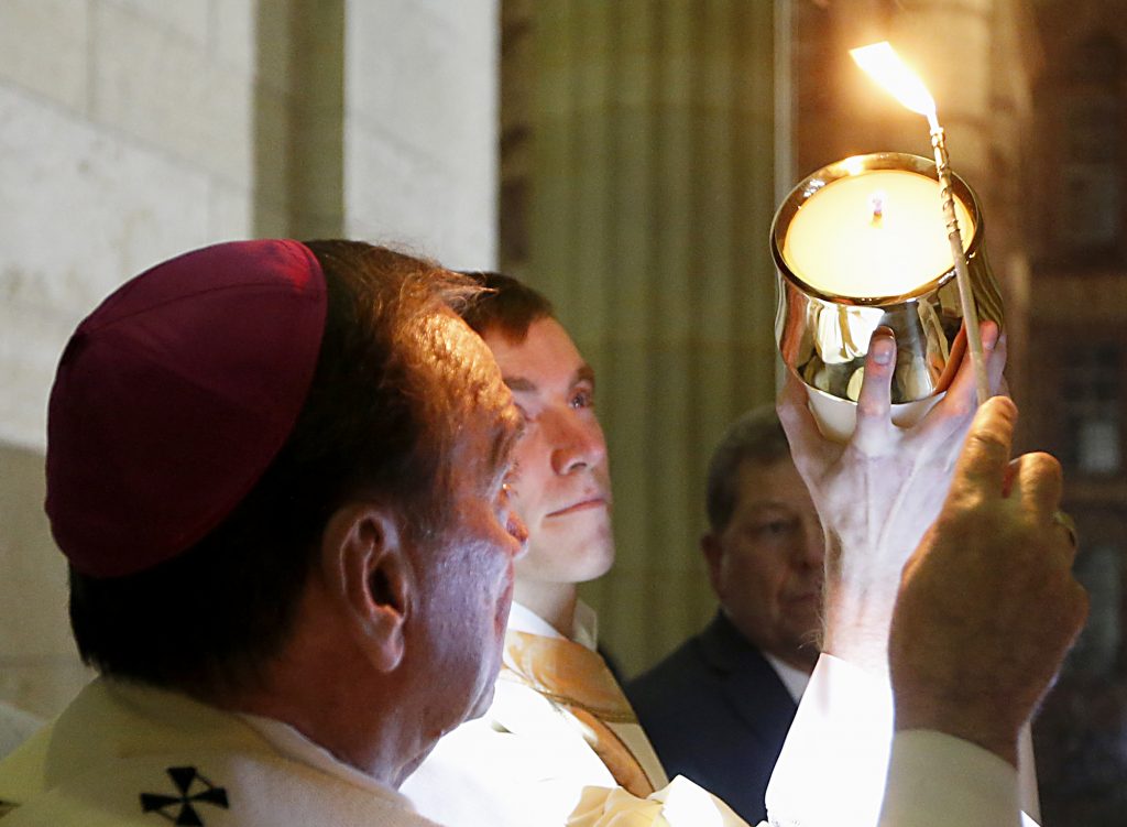 Archbishop Dennis Schnurr lights the Easter Candle, held by Deacon Jacob Willig, for the Easter Vigil in the Holy Night at the Cathedral of Saint Peter in Chains in Cincinnati, Holy Saturday, March 31, 2018. (CT Photo/E.L. Hubbard)