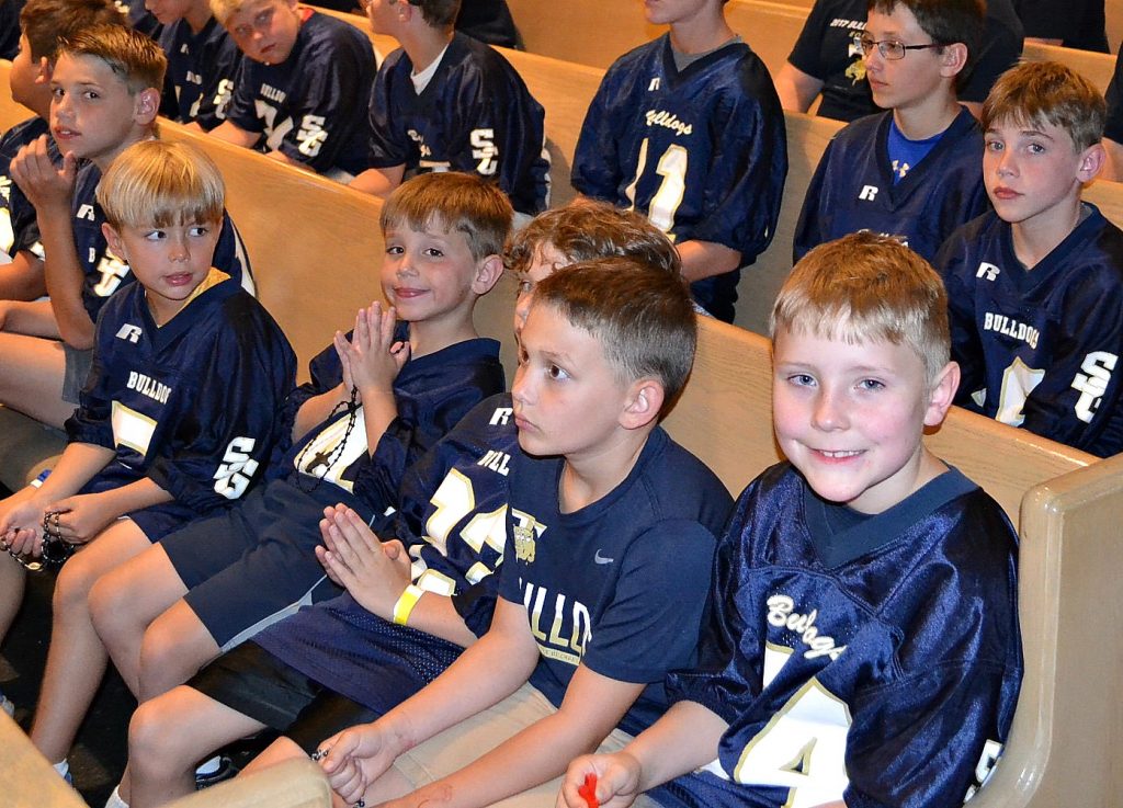 Boys from the St. Gertrude Football squad await praying the rosary. (CT Photo/Greg Hartman)