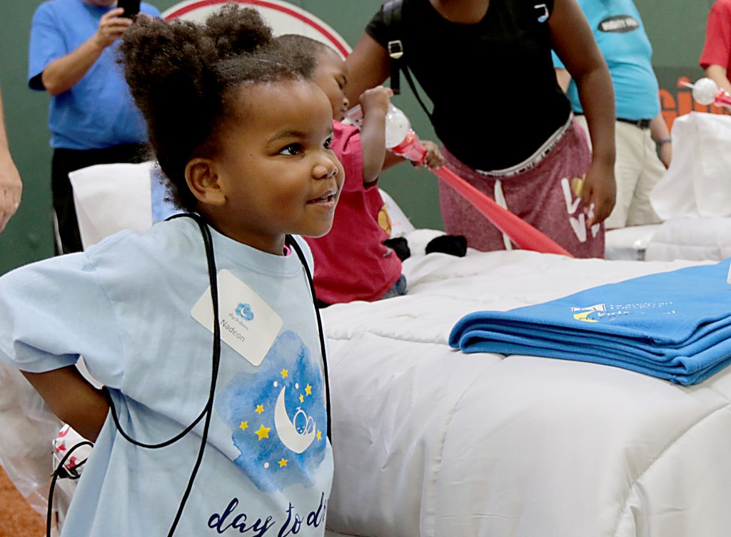 Nadeon Fitzgerald puts on her new backpack during the second annual “Day to Dream” event at the P&G MLB Cincinnati Reds Youth Academy in Roselawn Saturday, Aug. 25, 2018. St. Vincent de Paul - Cincinnati and Morris Furniture Company teamed up to provide 50 children in need with a bed of their own. (CT Photo/E.L. Hubbard)