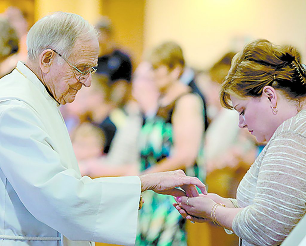 Father William Dorrmann delivers the Holy Eucharist to a parishioner during the St. Aloysius Parish 150th Anniversary Mass in Shandon Saturday, June 2, 2018. (CT Photo/E.L. Hubbard)