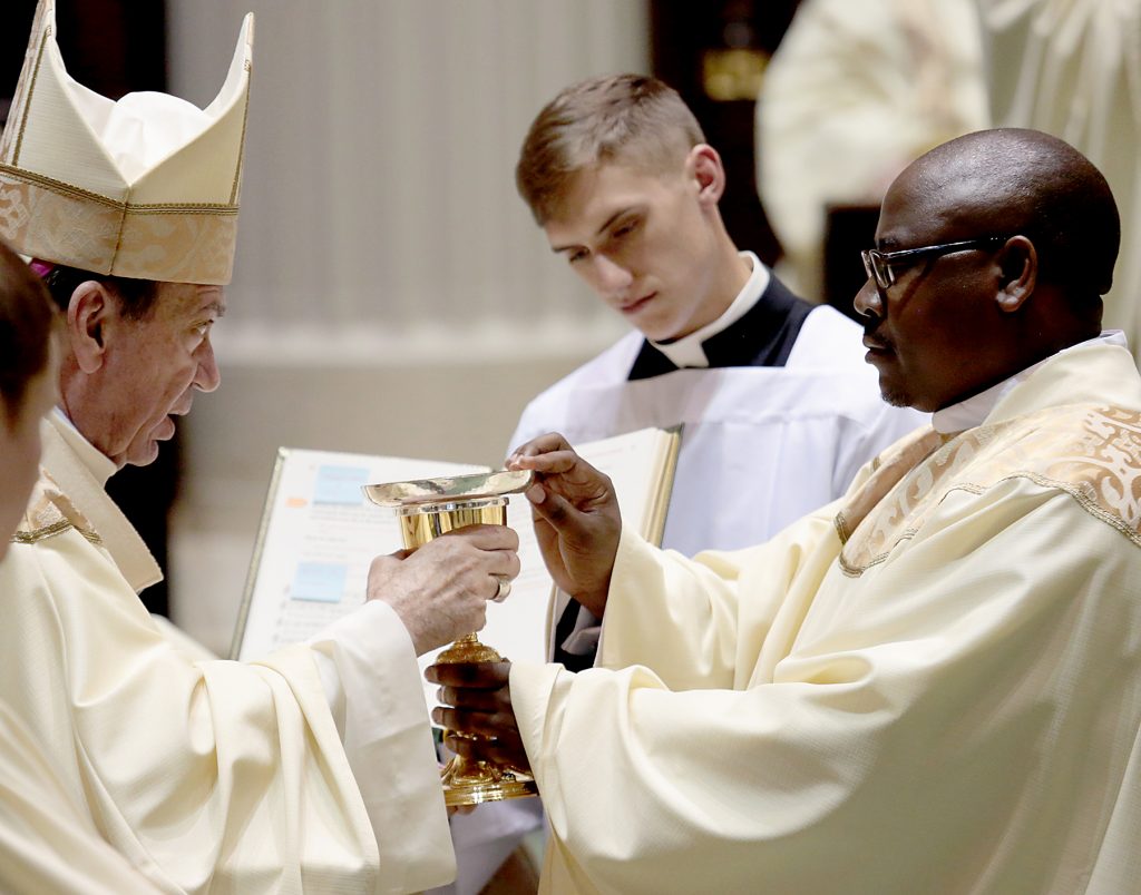 Father Elias Mwesigye receives the chalice and paten (CT Photo/E L Hubbard)