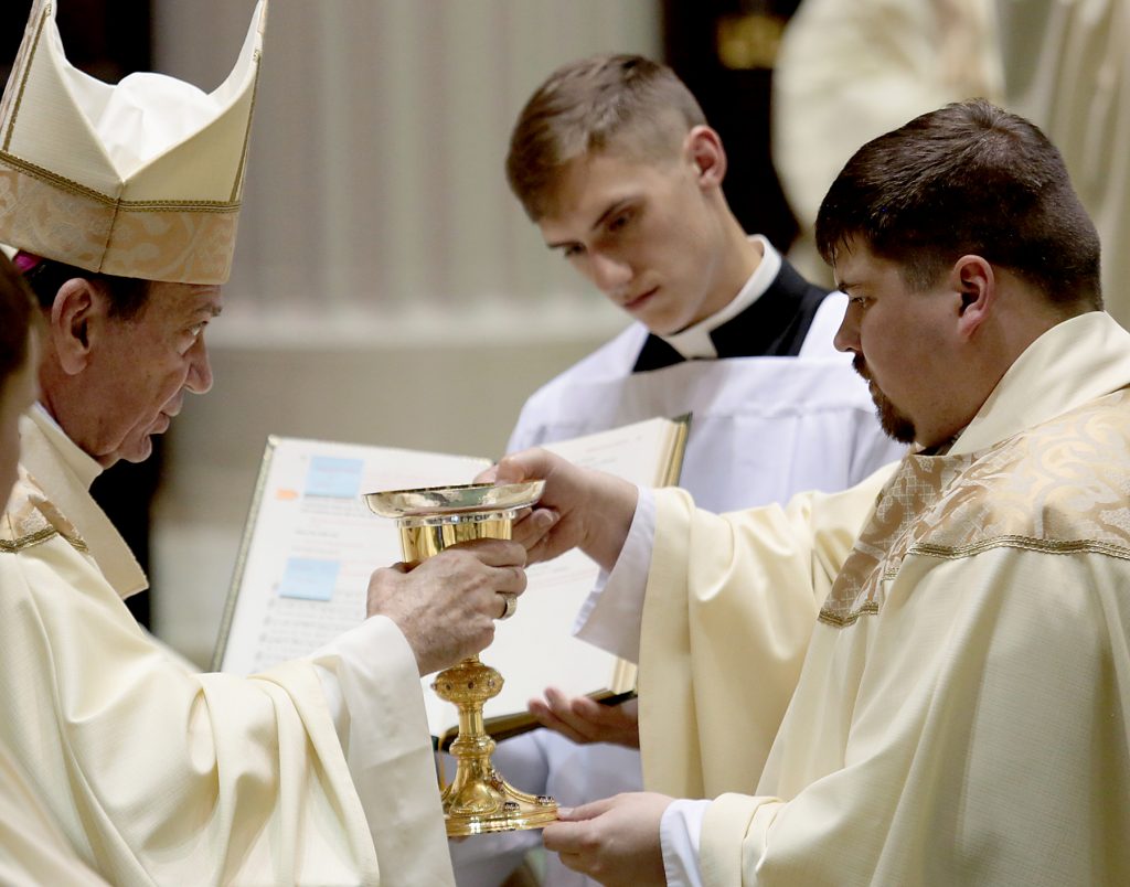 Father Mark Bredestege receives the chalice and paten. (CT Photo/E L Hubbard)