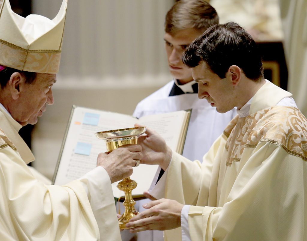 Father Andrew Hess receives the chalice and paten. (CT Photo/E L Hubbard)