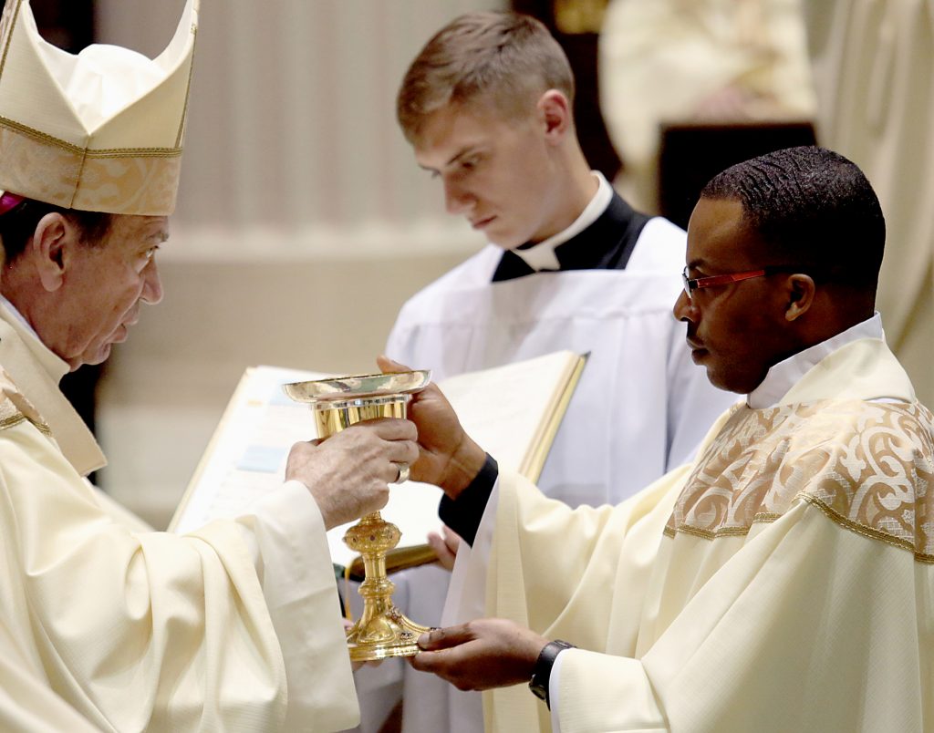 Father Alex Biryomumeisho receives the chalice and paten (CT Photo/E L Hubbard)