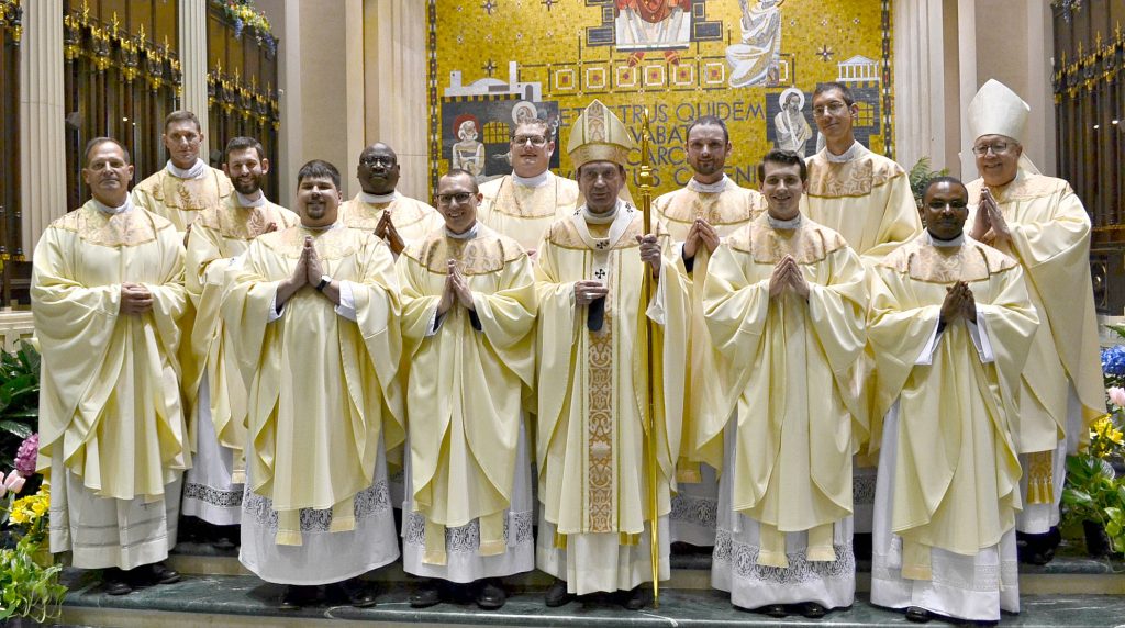 Front Row from L to R: Father Anthony Brausch, Father Mark Bredstege, Father Jeff Stegbauer, Archbishop Dennis M. Schnurr, Father Andrew Hess, Father Alex Biryomumeisho; Back Row L to R, Father Ambrose Dobrozsi, Father Elias Mwesigye, Father Zach Cecil, Father Jedidiah Tritle, Father Christian Cone-Lombarte, and Bishop Joseph Binzer (CT Photo/Greg Hartman)