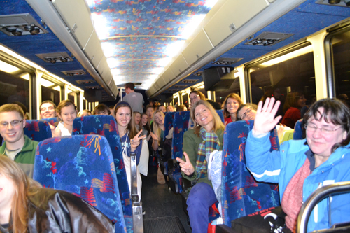 Students, staff, and other marchers on one of the buses wave goodbye.