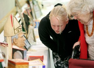 Eleanor Beringer, 11, and her grandmother, Florentine Brzozowski, examine the display featuring Pope John Paul II at the Polish Club Hall in Dayton Sunday, April 27, 2014. Brunch was served in the hall after a special Mass at St. Adalbert Parish to celebrate the Canonizations of Pope John Paul II and Pope John XXIII.