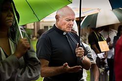 Father Robert Rosebrough, pastor of Blessed Teresa of Calcutta Parish in Ferguson, Mo., prays in the rain during a Aug. 16 service at the site of the death of Michael Brown. The unarmed teen was shot and killed Aug. 9 by a police officer. (CNS photo/Lisa Johnston, St. Louis Review) See SHOOTING-PRAYER Aug. 13, 2014.