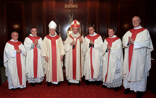 The newly ordained priest pose for a photo with key members of the clergy. From left are Rector of Mount St. Mary's Seminary Father Benedict O'Cinneslaigh, Father Adrian Hilton, Auxiliary Bishop Joseph R. Binzer, Archbishop Dennis M. Schnurr, Father Ethan Moore, Father Eric Wood and Archdiocese of Cincinnati Vocations Director Father Dan Schmitmeyer. (CT Photo/E.L. Hubbard)