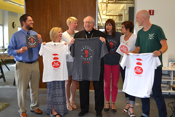Staff from HyperQuake and the Archdiocese of Cincinnati look at Auxiliary Bishop Joseph R. Binzer in a candid moment just after taking a group photo. HyperQuake is responsible for the branding of the Food for All campaign. (CT Photo/John Stegeman)