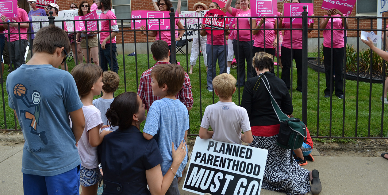 A family kneels to pray for the supporters of Planned Parenthood, while opposing the organization at a July 28 rally. Ohio Attorney General Mike DeWine announced Dec. 11 that Planned Parenthood affiliates in Ohio, including the one pictured here, have sent remains of aborted children to companies that disposed of them in landfills. (CT Photo/John Stegeman)