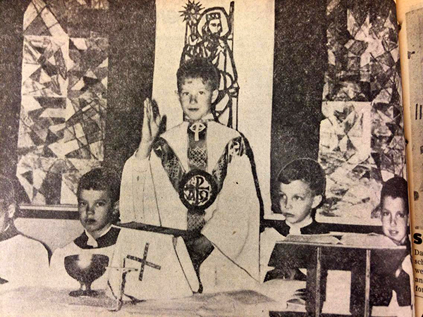 Second grade student Clark Monroe "blesses" his classmates during a practice "mass" as the students prepared for first communion at Our Lady of Mercy School in Dayton in 1966. The servers are, from left, Michael Zweisler, Scott Magoto, James Bennett, and Mark O'Connor. (CT File)