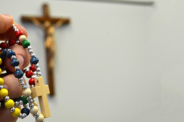 A hand holds a rainbow-colored rosary in front of a crucifix. Rainbow imagery is often associated with LGBTQ movements. Courage International, an apostolate for Catholics with homosexual desires, uses only a crucifix and the group's name as a logo. (CT Photo/John Stegeman)