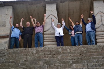 Some of the Archdiocese’s visitors and Honduran hosts pose like Rocky at a replica Mayan temple, after climbing dozens of steep steps (CT/Photo by Gail Finke)