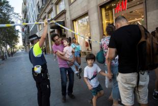 A police officer helps evacuate people after a van crashed into pedestrians in the Las Ramblas district of Barcelona, Spain, Aug. 17. Terrorists killed at least 12 and injured more than 50 others. (CNS photo/Ana Jimenez, La Vanguardia via Reuters)