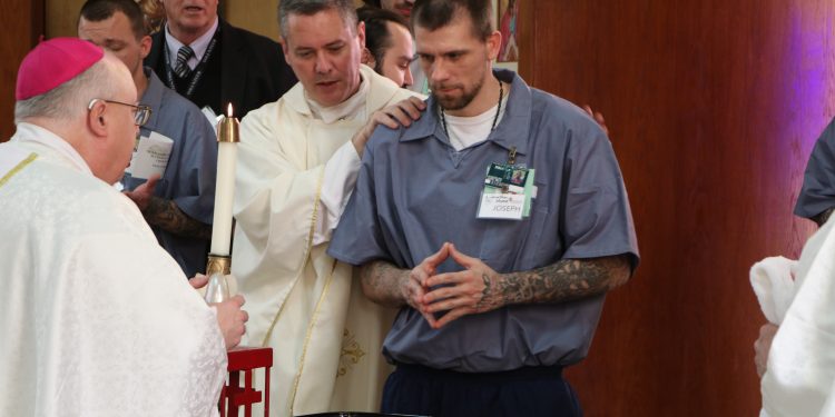 Joseph and his Sponsor receives the candle at baptism, Easter Vigil at Lebanon Correctional (CT Photo/Mark Bowen)