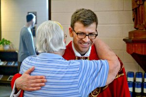 Rev. Craig Best receives a congratulatory hug from a parishioner at St. Margaret St. John (CT Photo/Greg Hartman)