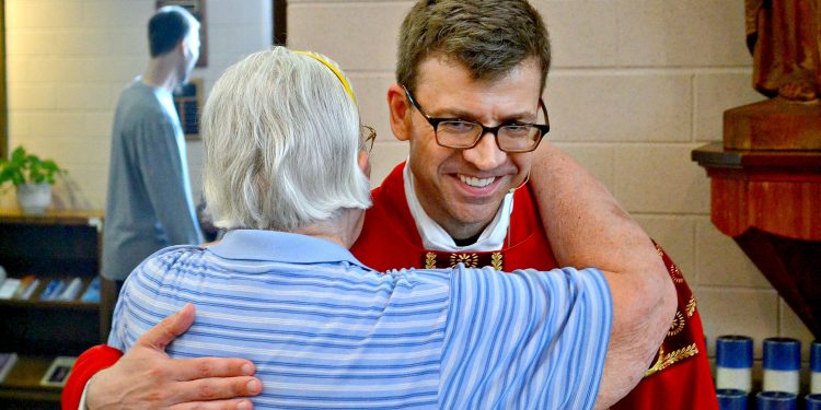 Rev. Craig Best receives a congratulatory hug from a parishioner at St. Margaret St. John (CT Photo/Greg Hartman)