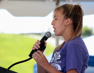 Allison Riegler sings “God Bless America” during the Cross the Bridge for Life celebration on Riverboat Row in Newport, Sunday, June 3, 2018. (CT Photo/E.L. Hubbard)