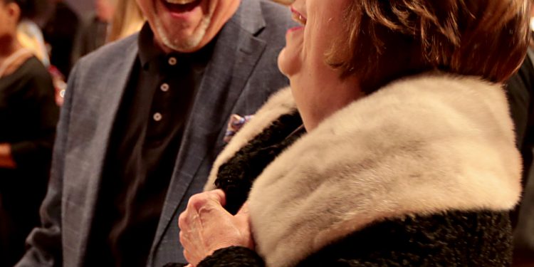 Kathy Qualls shares a laugh with David Ferguson as she decides to purchase the coat she is trying on during RetroFittings 2018, a St. Vincent de Paul fundraising event, at Music Hall in Cincinnati Thursday, Oct. 18, 2018. (CT Photo/E.L. Hubbard)