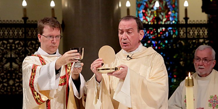 Archbishop Dennis Schnurr prepares the Holy Eucharist for the Mass of Thanksgiving for the 150th Anniversary of the Arrival of the Little Sisters of the Poor in Cincinnati at St. Monica-St. George Parish in Cincinnati Saturday, Oct. 20, 2018. (CT Photo/E.L. Hubbard)