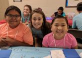 Kylie Schmidt with Savannah Hoover in the background poses with two Navajo children at Summer Bible School. (Courtesy Photo)