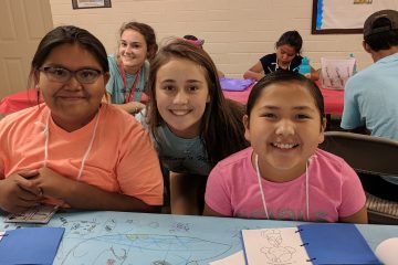 Kylie Schmidt with Savannah Hoover in the background poses with two Navajo children at Summer Bible School. (Courtesy Photo)