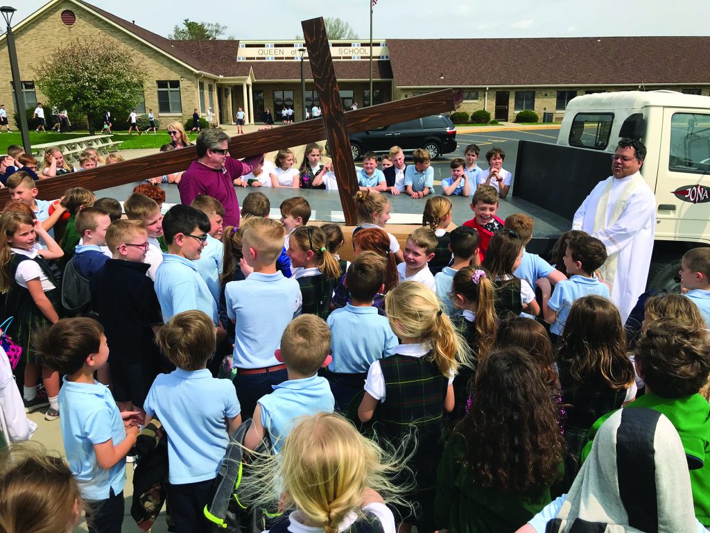 Queen of Peace Parish in Hamilton replaced their outside cross atop the church that was originally built and erected in 1966. The new cross is larger and lit for the entire Queen Acres neighborhood. They placed the old cross inside the new one. Students witnessed the blessing of the new cross.