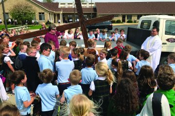 Queen of Peace Parish in Hamilton replaced their outside cross atop the church that was originally built and erected in 1966. The new cross is larger and lit for the entire Queen Acres neighborhood. They placed the old cross inside the new one. Students witnessed the blessing of the new cross.