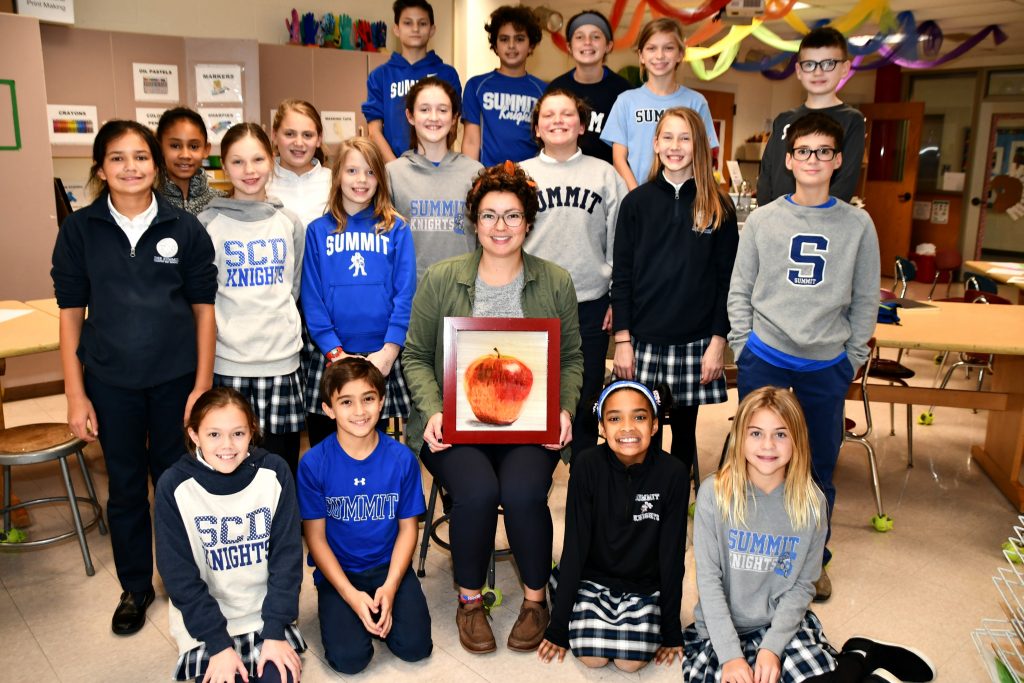 Samantha England with sixth graders at Summit Country Day School. She holds her painting of an apple, part of her personal perseverance project