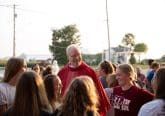 Priest wearing red stands among group of young women