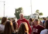 Priest wearing red stands among group of young women