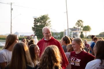 Priest wearing red stands among group of young women
